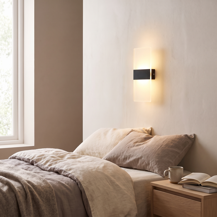 Black Pulse rechargeable wall light glowing above a bedside table